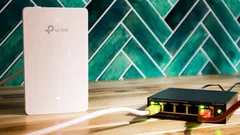 Bílý TP-Link WiFi AP s černým 5portovým PoE gigabit switchem na dřevěném stole