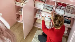 Žena organizuje prádlo ve skříni v růžovém pokoji, úklid a uspořádání domácnosti