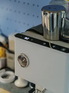 Bílý espresso kávovar s chromovým džbánkem a ukazatelem