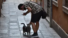 Muž v černém se psem s krátkou srstí při setkání s místními