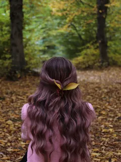 mladá dívka s dlouhými kudrnatými vlasy sedí v listí