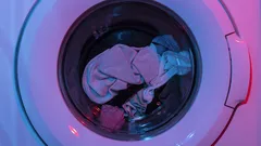 Růžový a zelený plastový kontejner vedle prádelního stroje