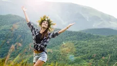 Žena se zvednutýma rukama na pozadí lesnaté karpatské hory v létě