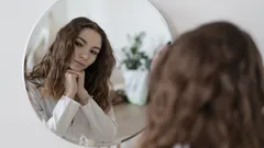 Žena se dívá na svůj odraz v zrcadle