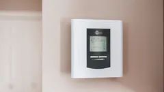 Bílý a šedý termostat nastavený na 19,5 °C