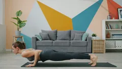 Žena cvičí plank a jógový downward dog doma na podložce
