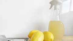 Domácí čistič z citronové kůry a octa vedle průhledné lahve